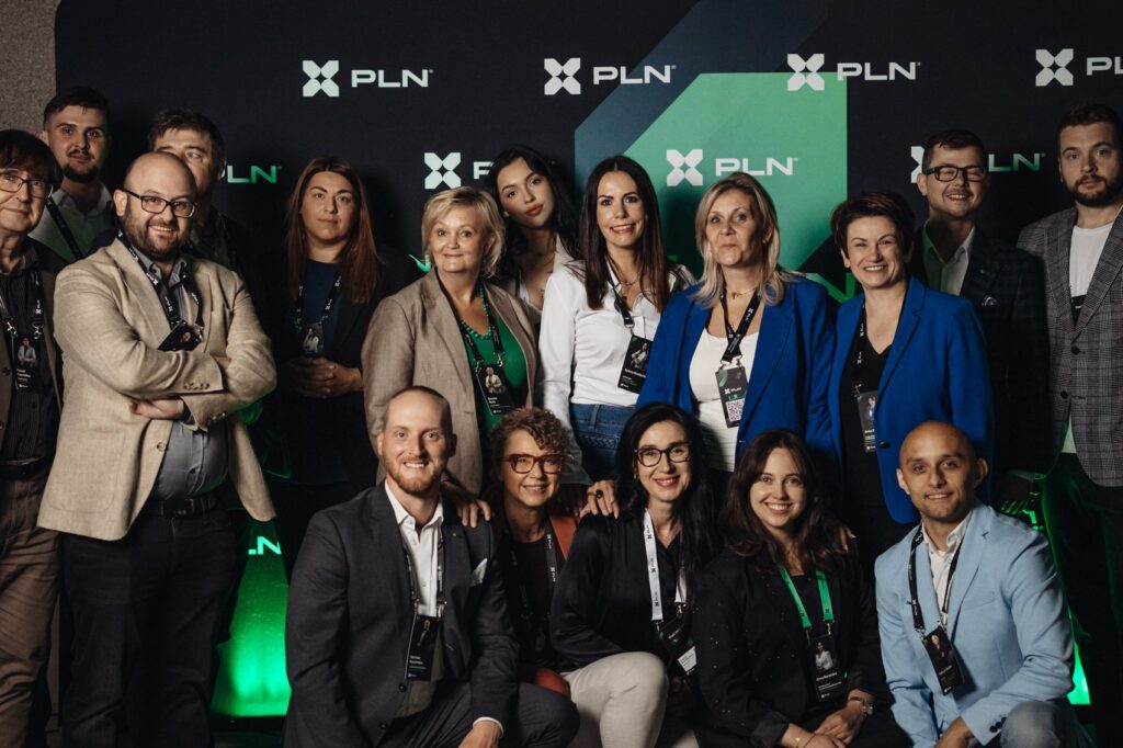 Zdjęcie grupowe uczestników Planety Networku przy ściance Organizacji PLN